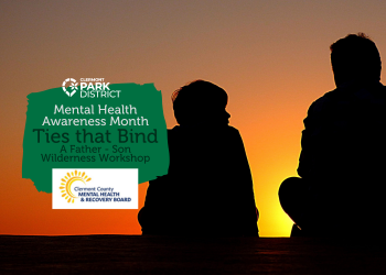 A young boy looks at his father, their figures silhouetted by sunset